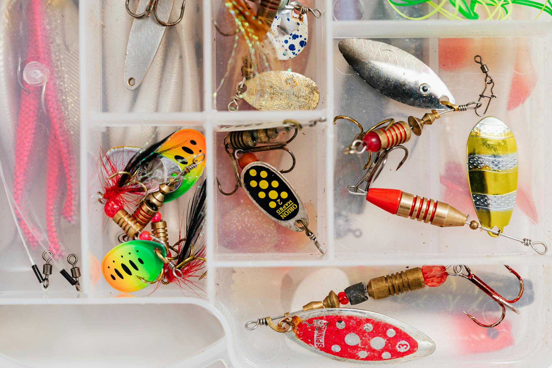 Assorted fishing lures in a tackle box, perfect for angling enthusiasts.